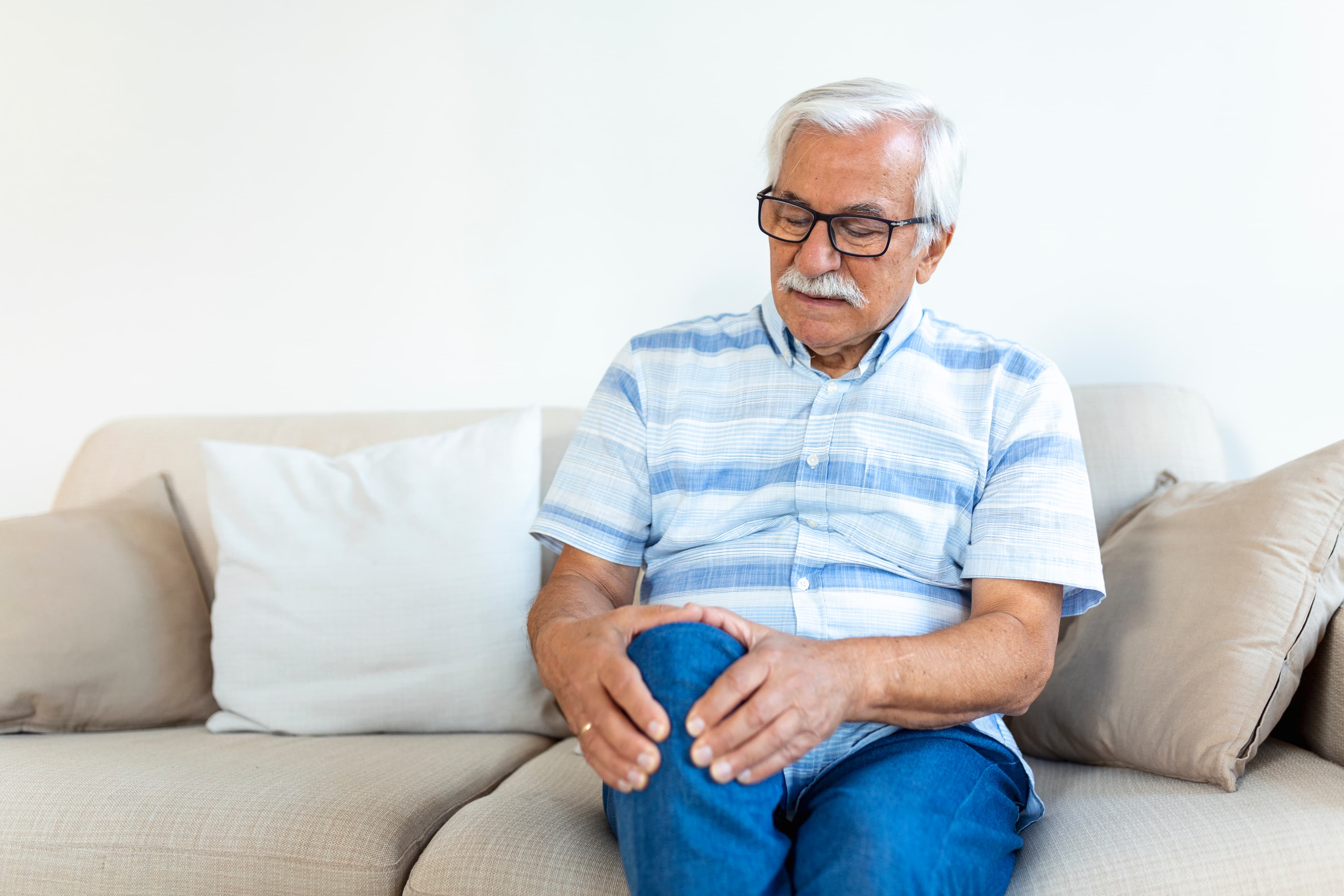 An elderly person receiving gentle physiotherapy for arthritis in their home in Delhi.